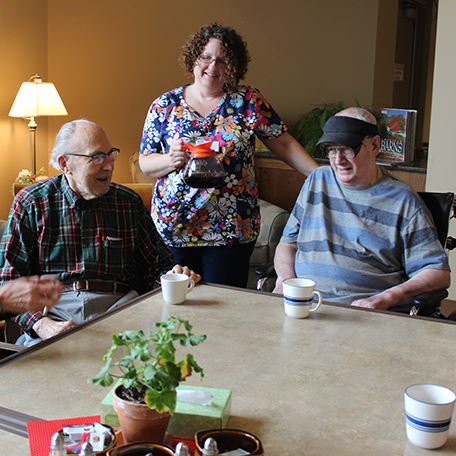A healthcare provider pouring coffee for residents of a community-based residential facility