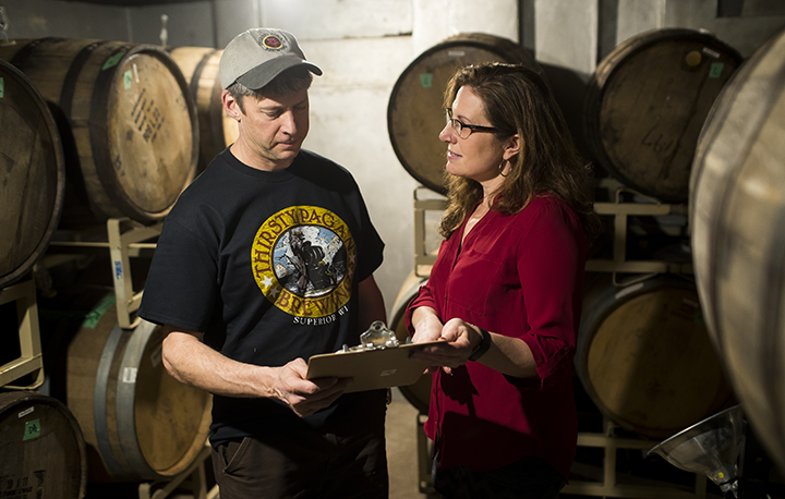 Graduate does accounting for Thirsty Pagan Brewing in room full of barrels.