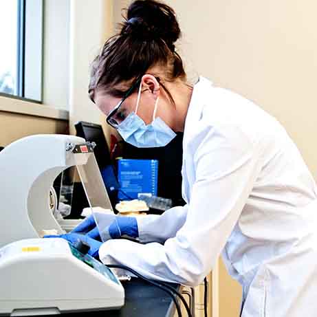 Dental Assistant student looking through a microscope