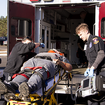 Paramedic students loading a stretcher onto an ambulance