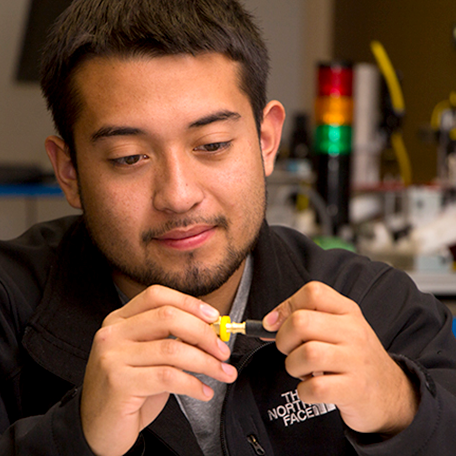 A student looking at a part used in mechatronics