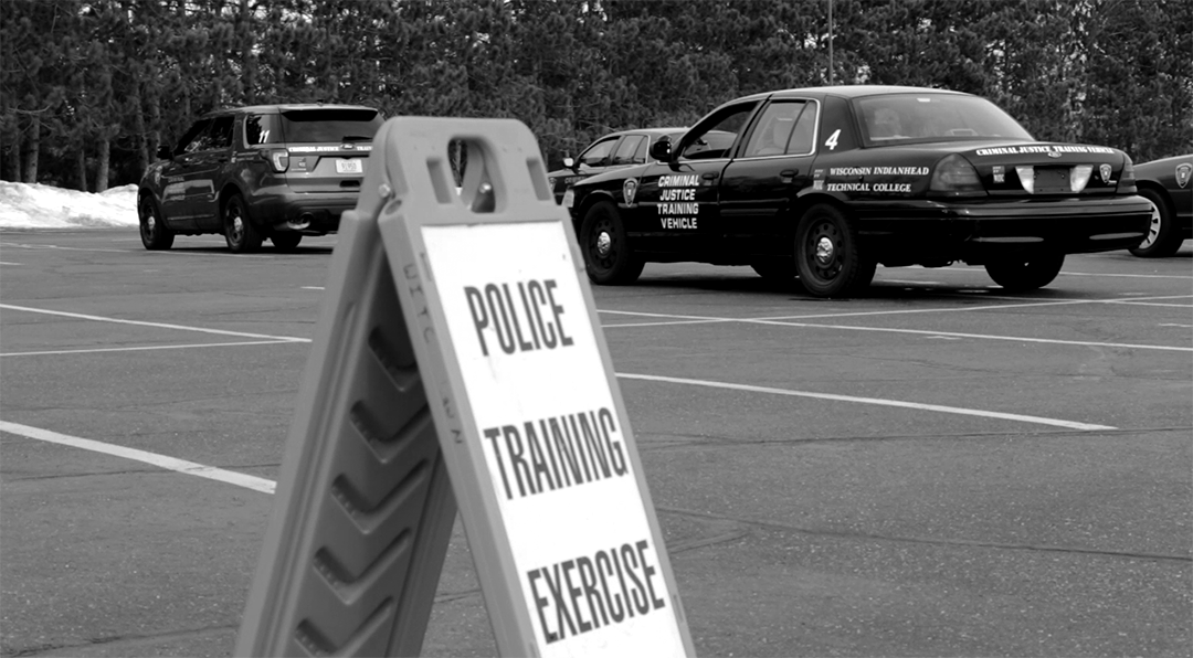 A training exercise caution sign with a police car in the background