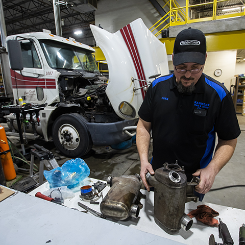 A diesel repair technician analyzing parts in a shop