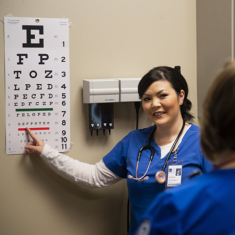 A medical assistant student performing an eye exam on a student patient