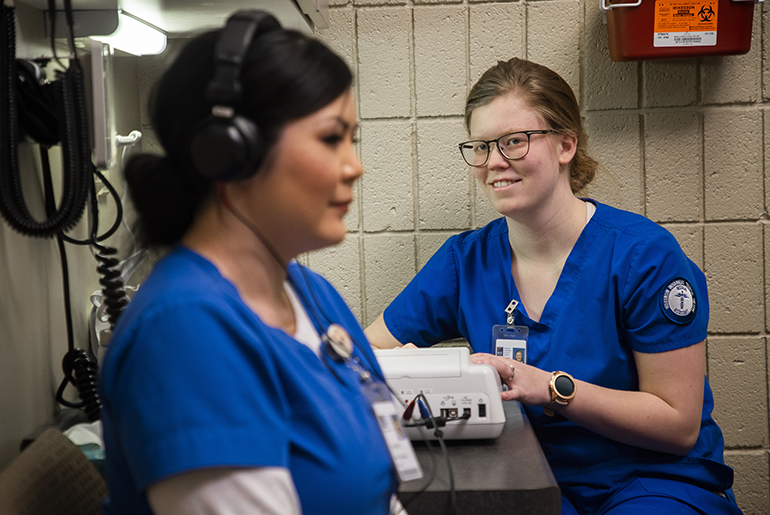 Two cma students practicing administering a hearing test in a doctor's office