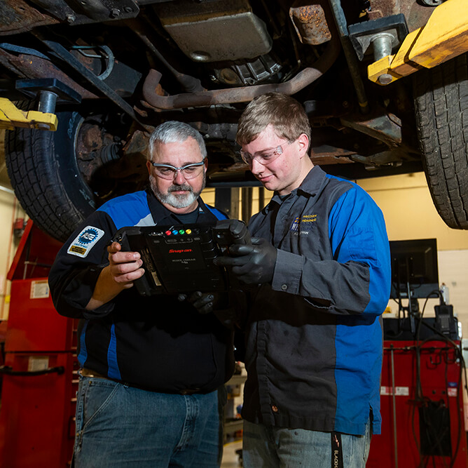 An automotive student and instructor looking at technology used in the automotive industry