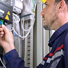 Broadband technician checking cable on electrical panel