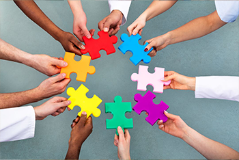 group of diverse hands forming a circle, holding puzzle pieces