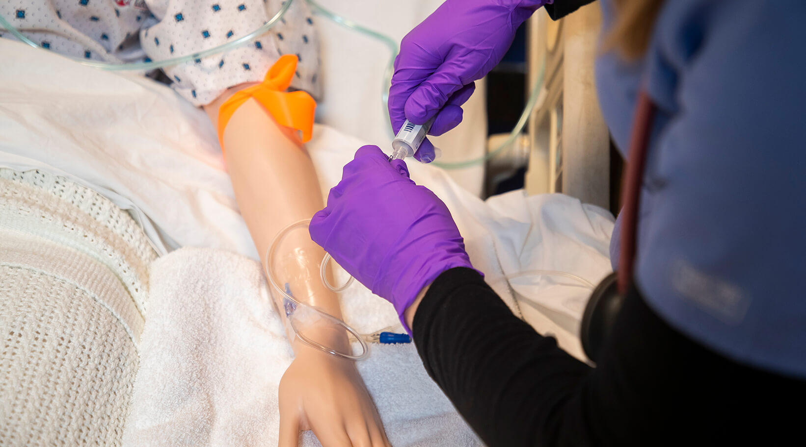Students practicing using syringes on a simulated patient