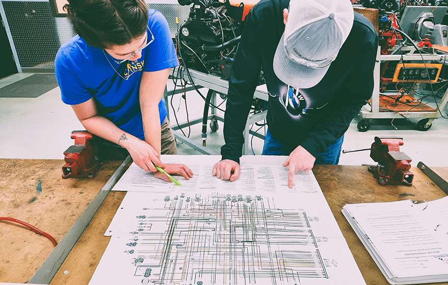 2 students looking at electrical map in the lab