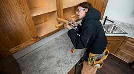 A student working on cabinetry in a house