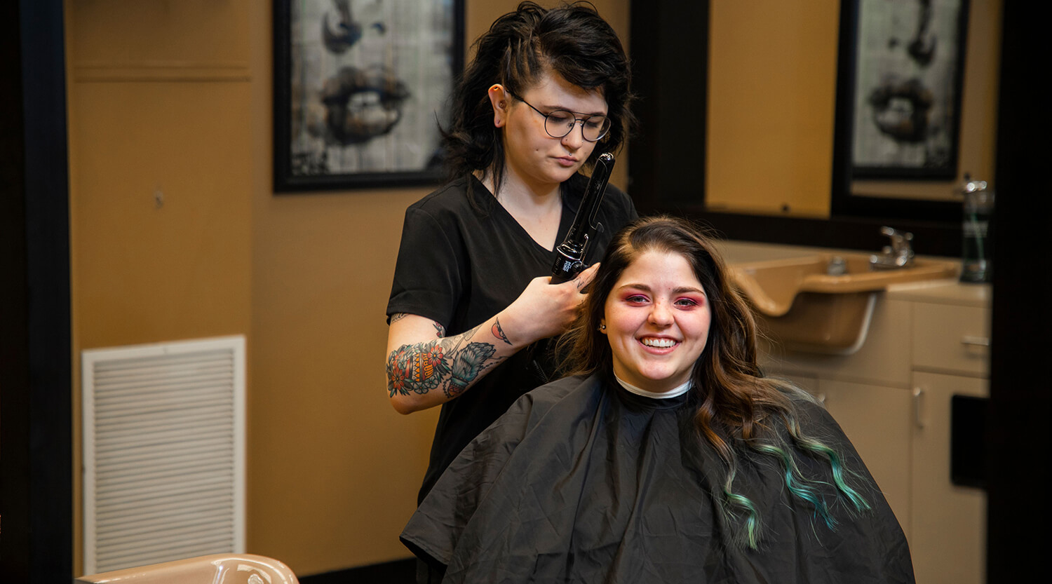 A cosmetology student working on a client's hair