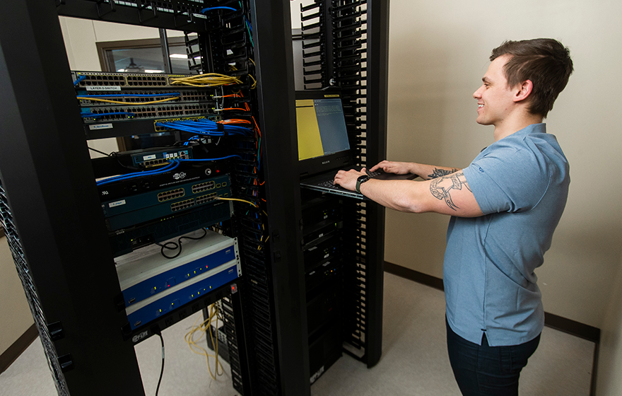 An IT - Cybersecurity Specialist student working hands-on with classroom technology