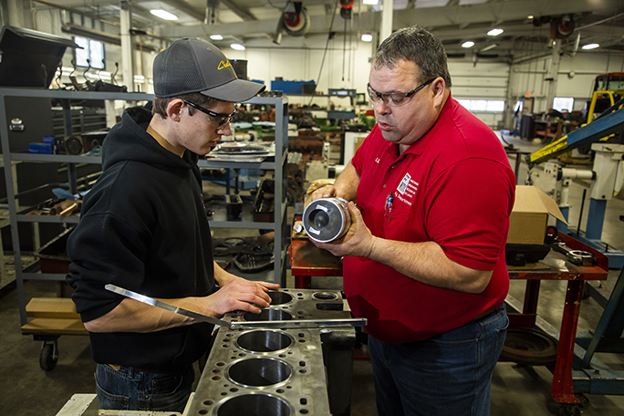 An instructor and student examining diesel equipment