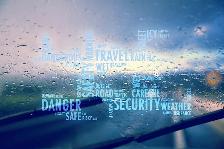 Driving simulator word cloud with various driving hazards overlay an image of driving in a rainstorm