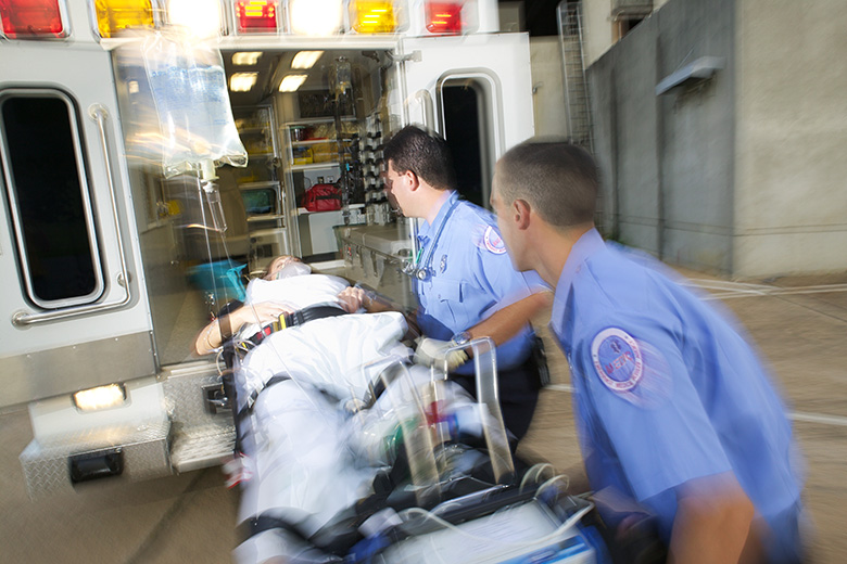 Paramedics load a patient into the back of an ambulance