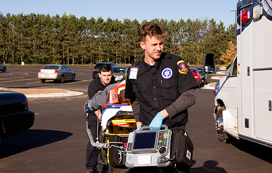 An Emergency Medical Technician in training, carrying a stretcher