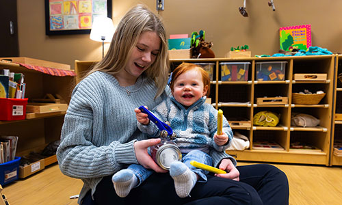 Early Childhood Education student teaching a toddler how to make music