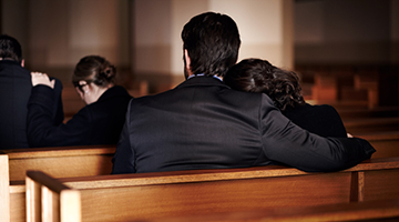 2 people grieving in a church pew