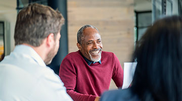 Older man leading discussion to a group of peers