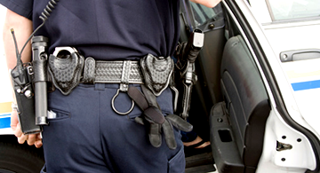 Police officer standing by a car with a view of the belt with all the equipment police officers use