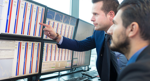 Two financial analyst looking at stocks on a computer screen