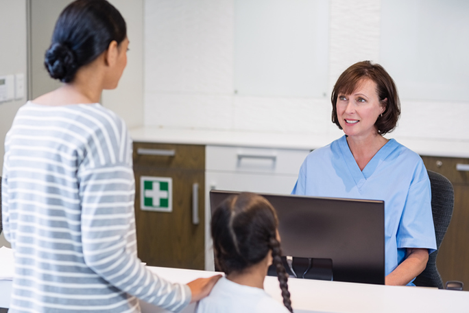 A medical administrative professional greeting patients at the front desk