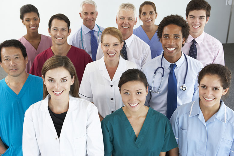 11 healthcare professionals dressed in colorful scrubs or professional wear,  standing in a group and smiling