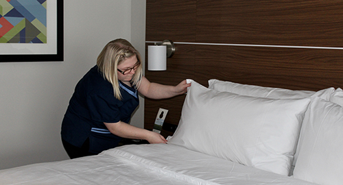 A student making a bed in a hotel