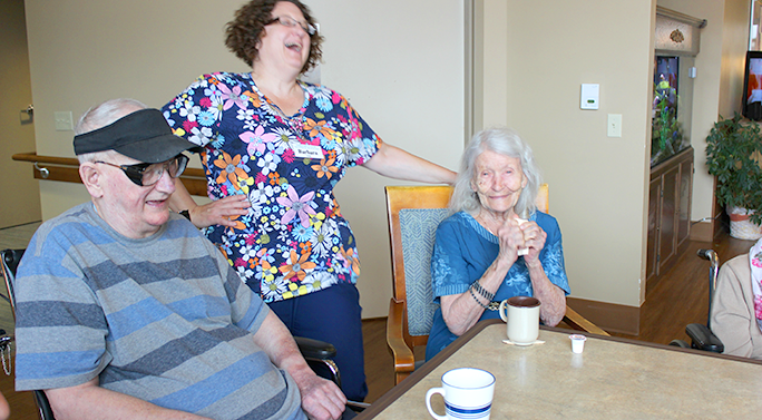 A caregiver at a CBRF laughing with residents