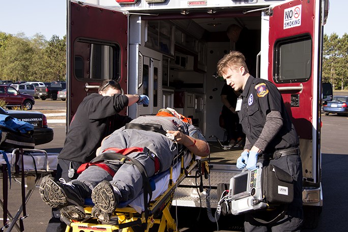 Paramedic students practicing loading a stretcher into an ambulance