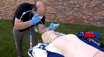 An EMT student using the tools of the trade to simulate a real life scenario