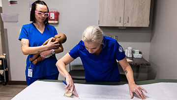 Medical assistant students learning how to measuring a baby 