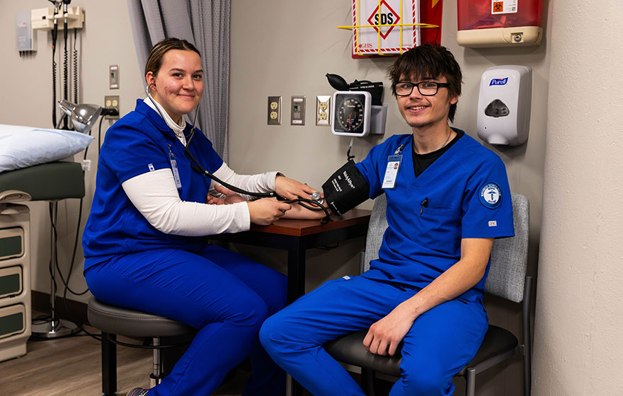 A medical assistant student checking blood pressure on a student patient