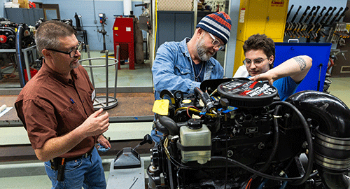 2 students working on motor and instructor talking