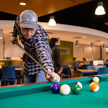 Student playing pool in the Ashland common area