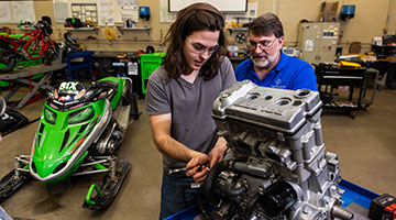 Student working on an engine with instructor supervision