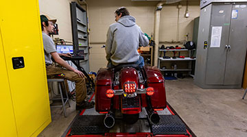 A student testing a motorcycle in the lab