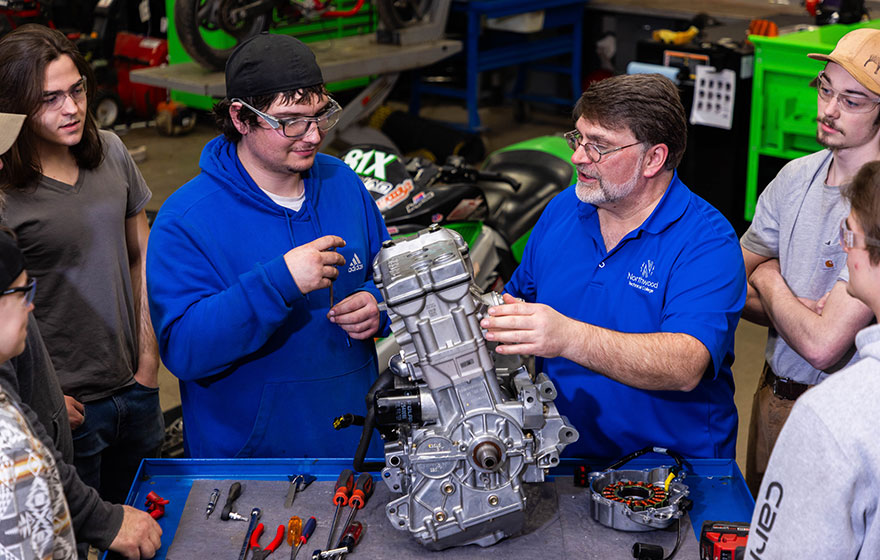 An instructor working with students in power sports lab