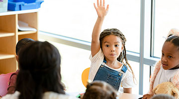 Little girl raises hand during preschool class