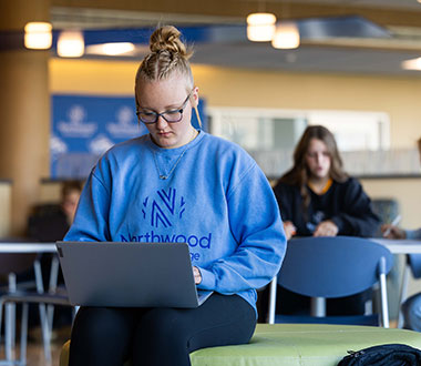 Northwood Tech student doing homework on laptop in commons area