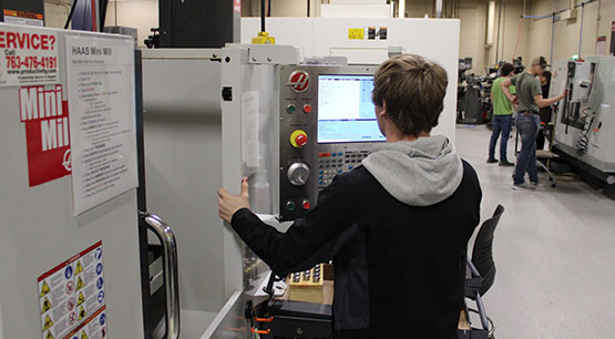 A student working intently with a machine part
