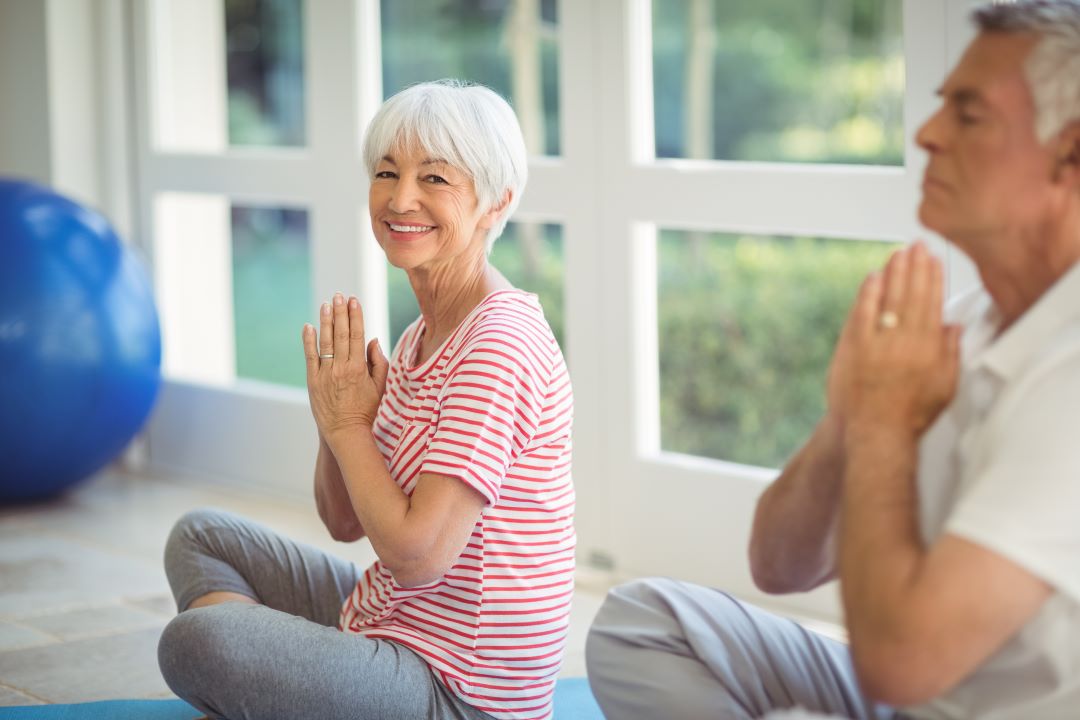 two older adults sitting in a room on yoga mats