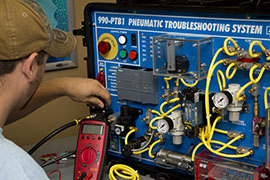 A student works on simulation equipment for pneumatics