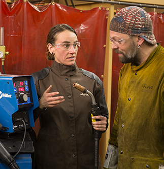 Female welding instructor works with a male student