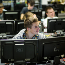 Student in computer lab classroom smiling at other students